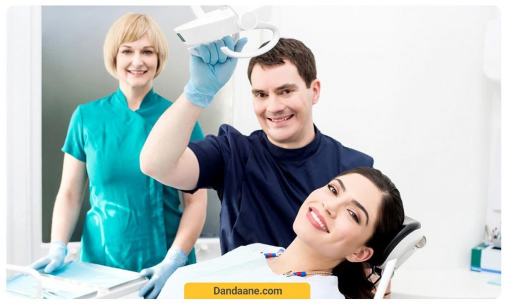 تصویر یک بیمار که برای کشیدن دندان  روی یک یونیت دراز کشیده و در حال لبخند زدن است